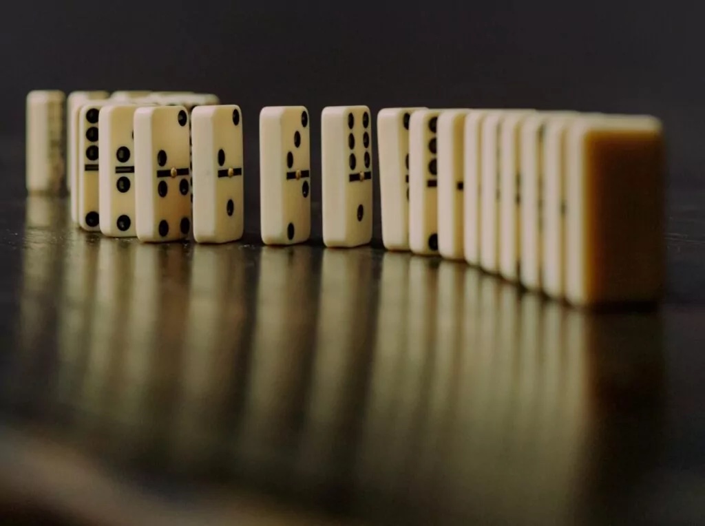 Dominoes stood on-end in a waving row against a dark background