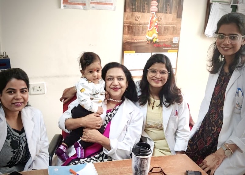 Dr. Shelly Batra, an ob-gyn based in India, holds a pediatric patient and smiles for a photo with her non-profit team.