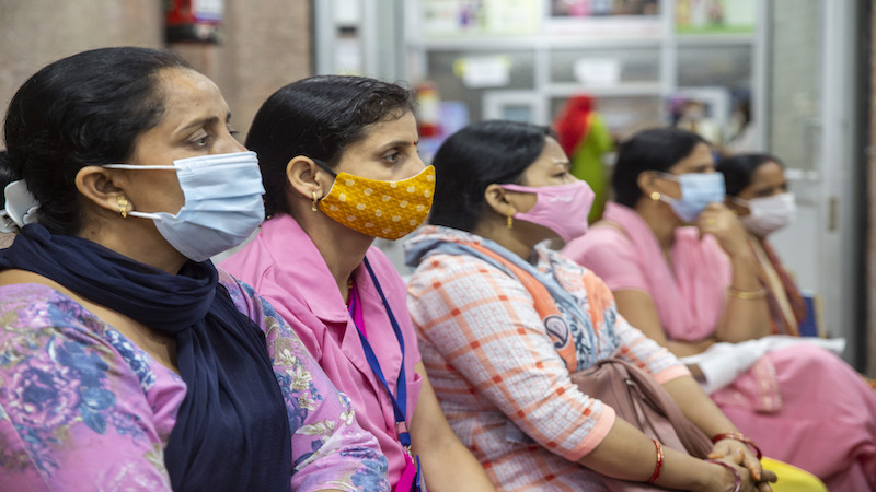 Female Indian health care providers sit in a row, listening