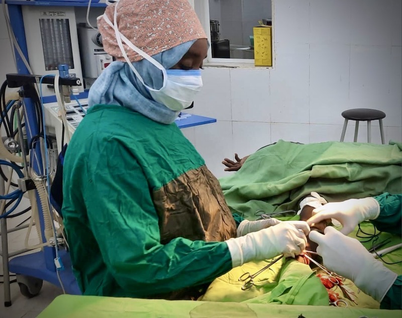 Dr. Alaa Mohammed, a Sudanese physician, wears green scrubs and operates on a patient.
