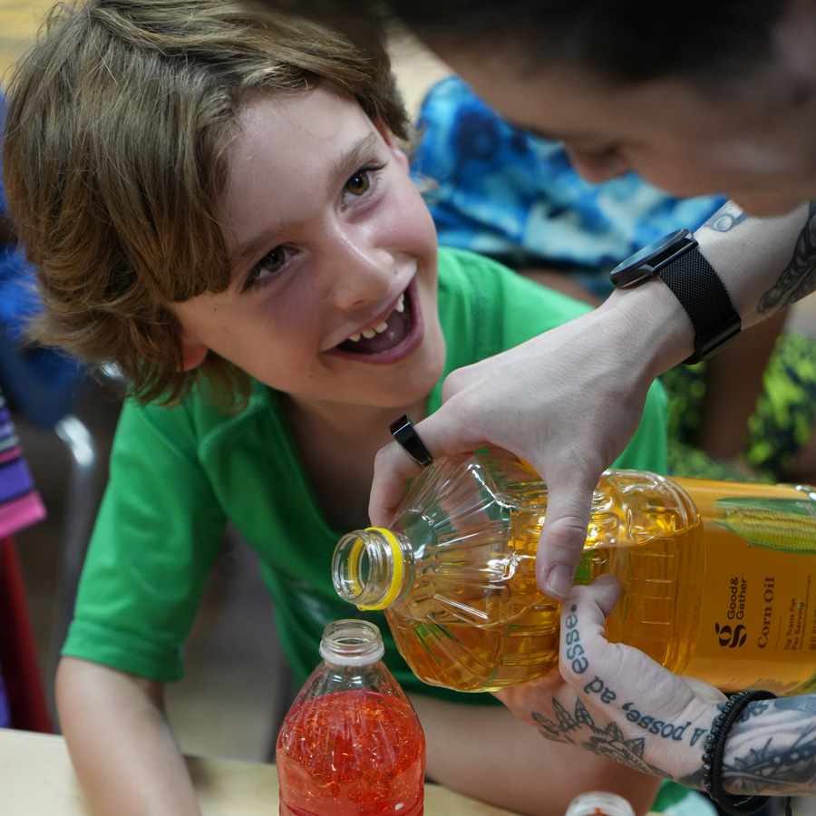 Child watching juice being poured into bottle.