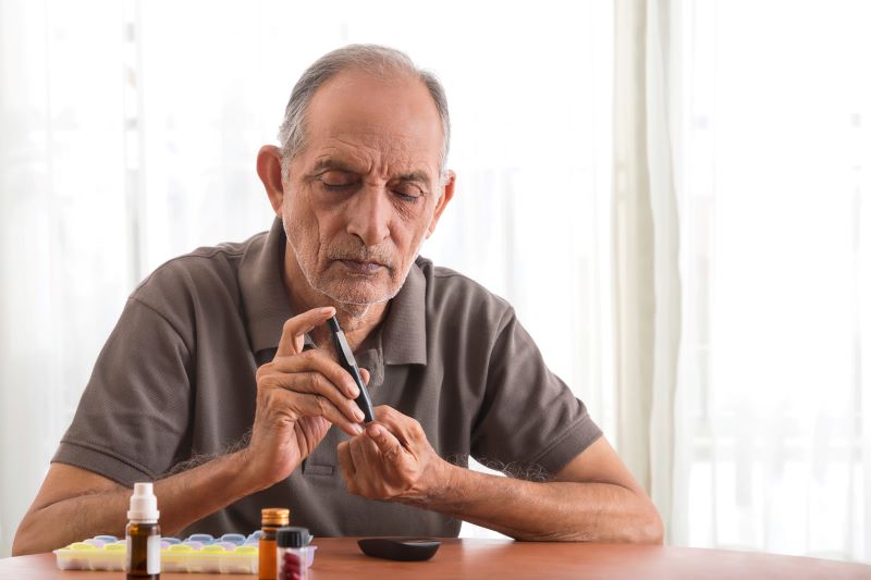 A stock photo of man pricking his finger to monitor blood sugar levels.