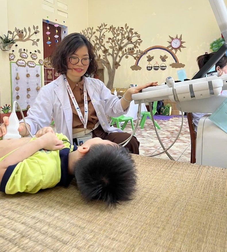 Smiling, a female doctor holds an ultrasound on a child's stomach