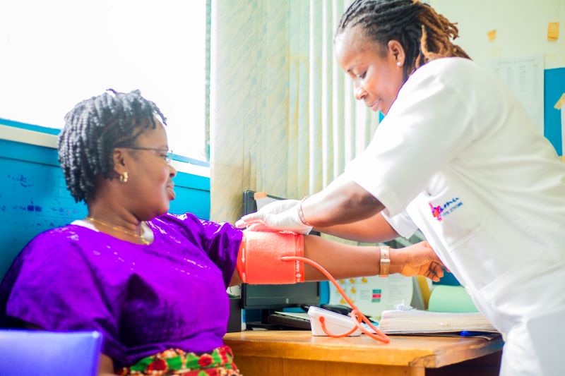 A female patient extends her arm as her female provider wraps a blood pressure cuff around her arm in Cote d'Ivoire.