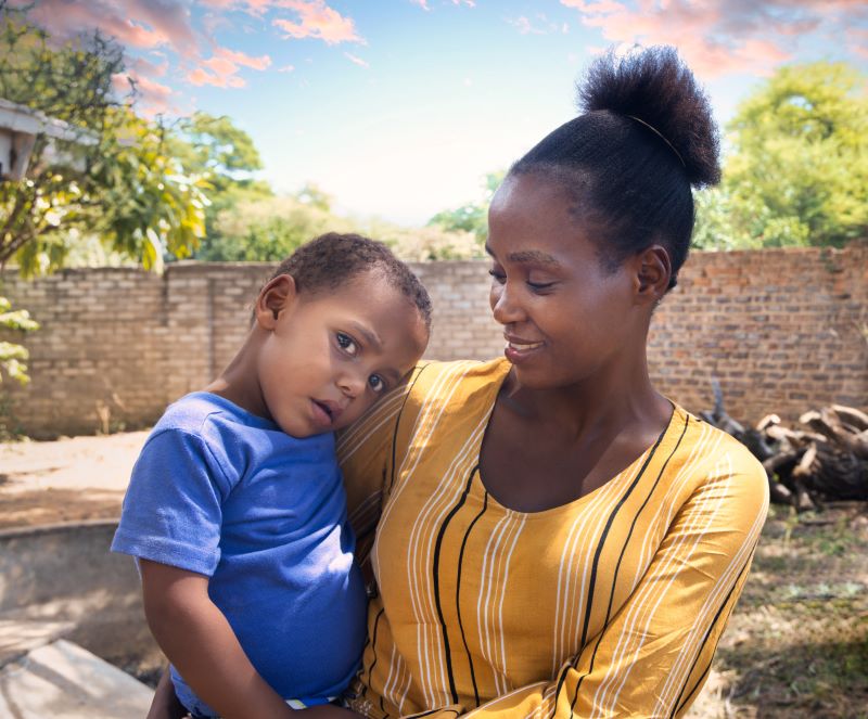 A stock image of an African woman holding a young male child in her arms.