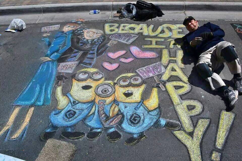Saul lays on the cement next to his chalk drawing of Despicable Me