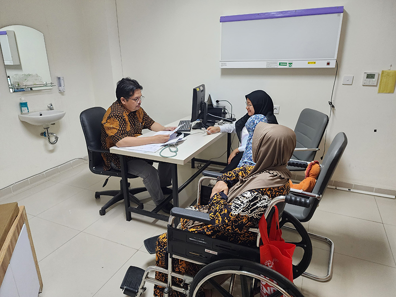 Dr. Rouly Pasaribu speaks with a lung cancer patient and their family in his hospital office
