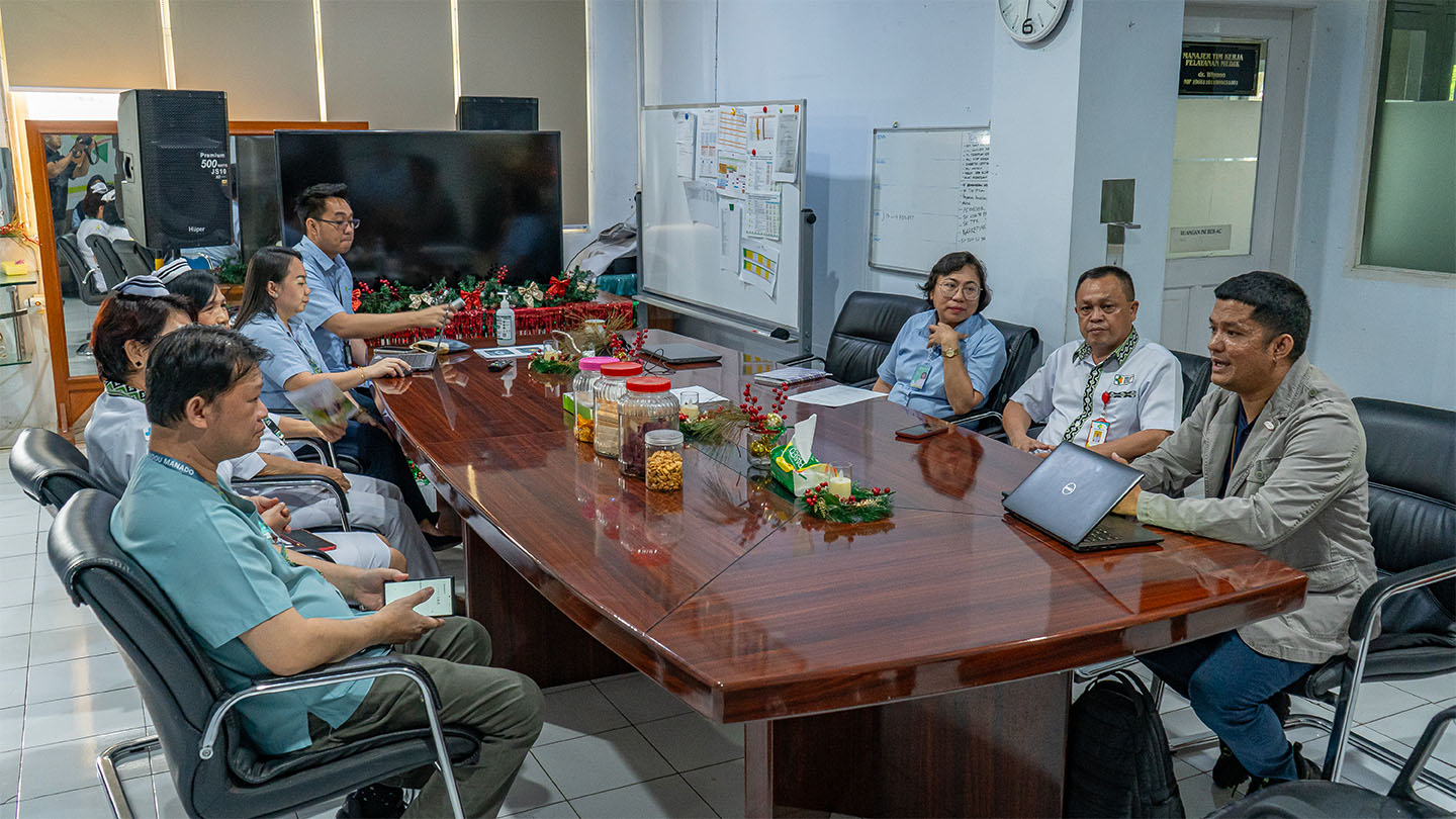 A group of health care providers in Indonesia sitting around a conference room table having a discussion.