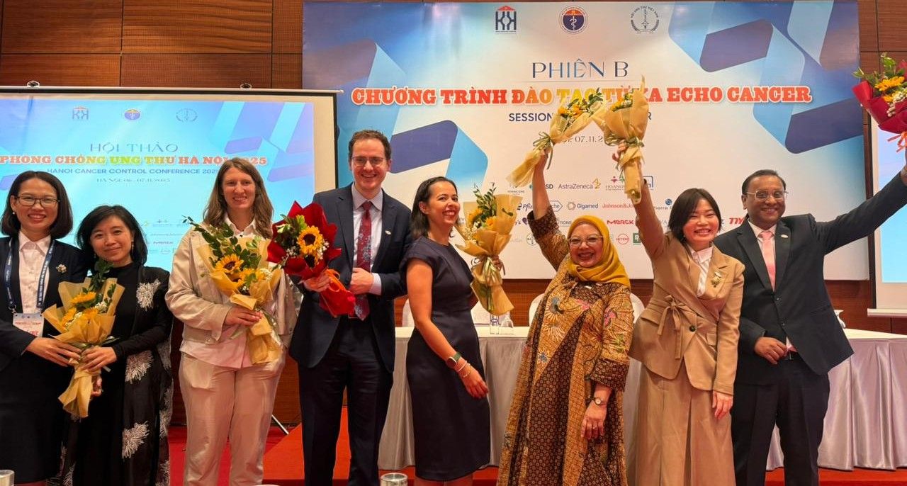 The ECHO cancer panelists at the Hanoi Cancer Control Conference hold flowers and celebrate.