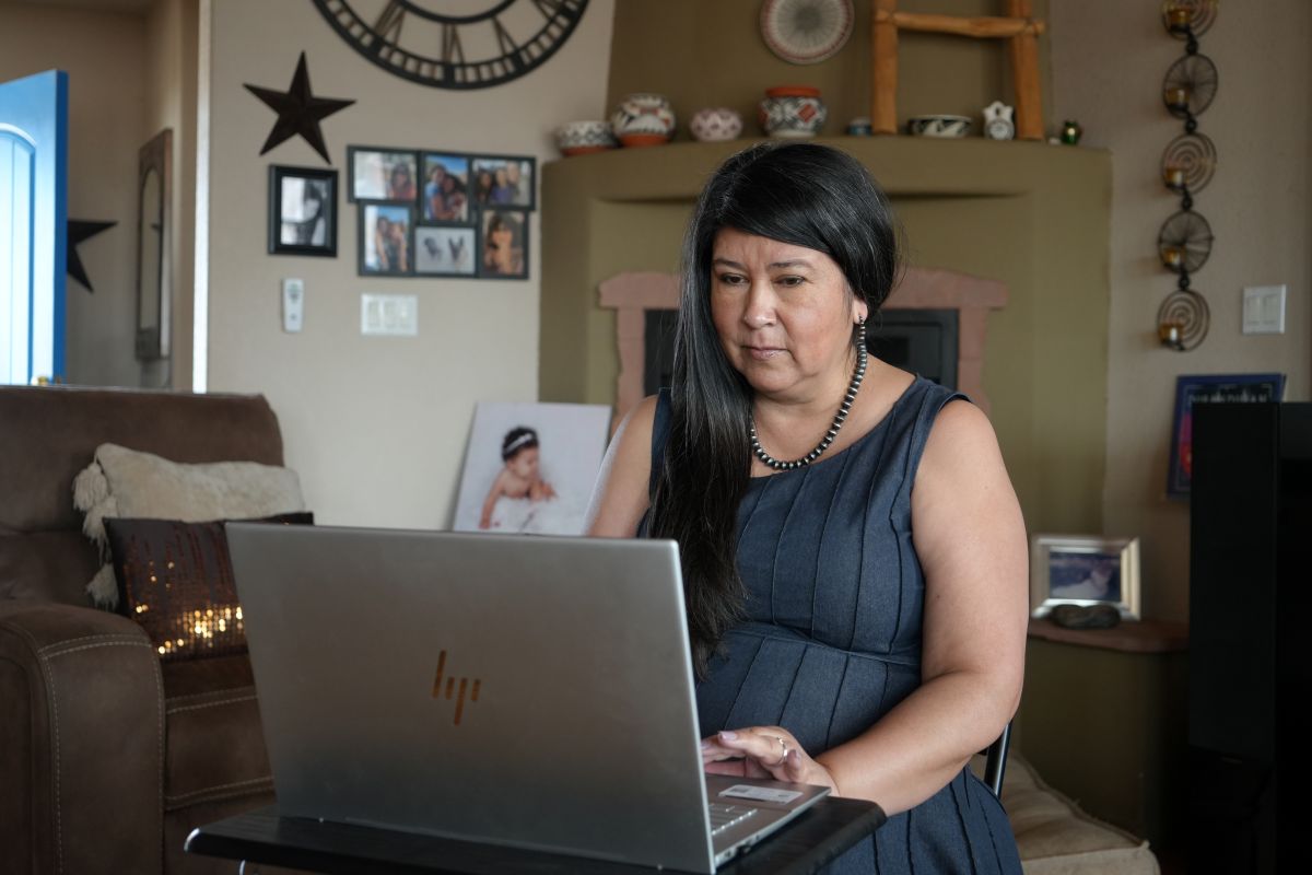 Liz Martinez sits in her home looking at a laptop
