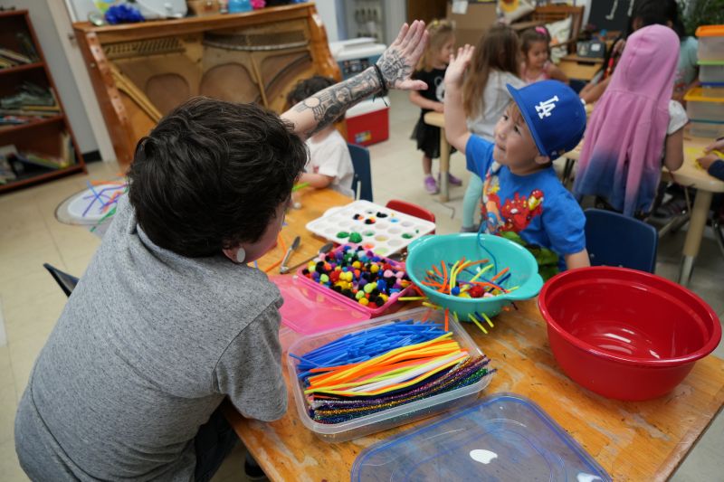Teacher and student high-five each other while crafting