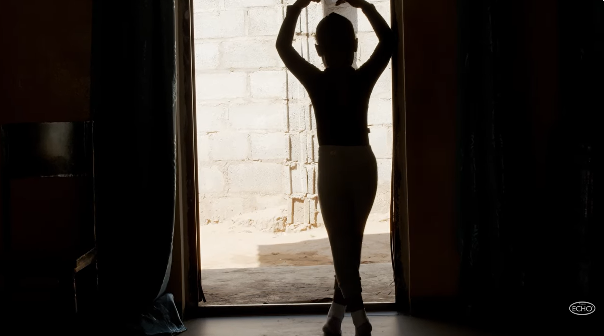 The silhouette of a little girl dancing in a doorway. 