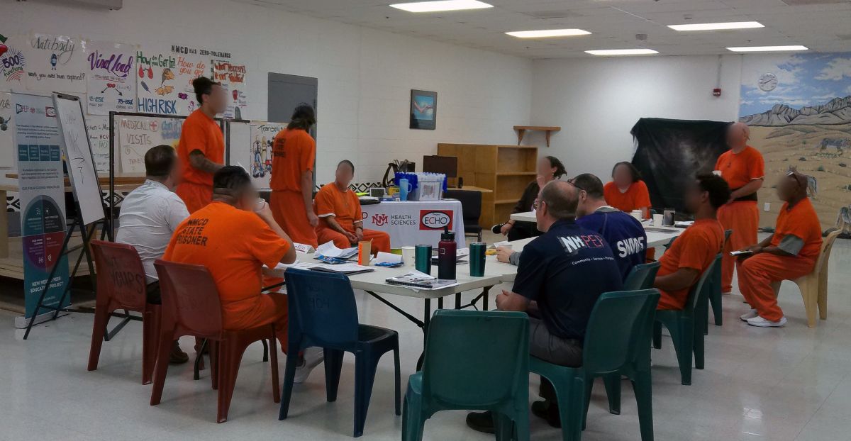 A group of men, some wearing orange jumpsuits, some wearing NM PEP t-shirts.