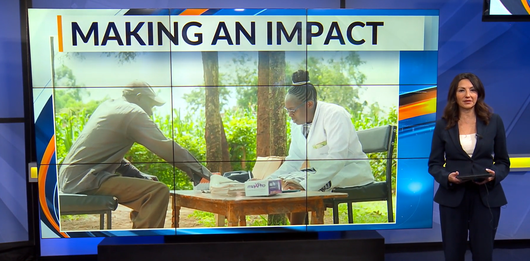 A female news anchor stand to right of large screen. Reads "Making an impact" behind, a male (left) patient and female doctor sit at a table.