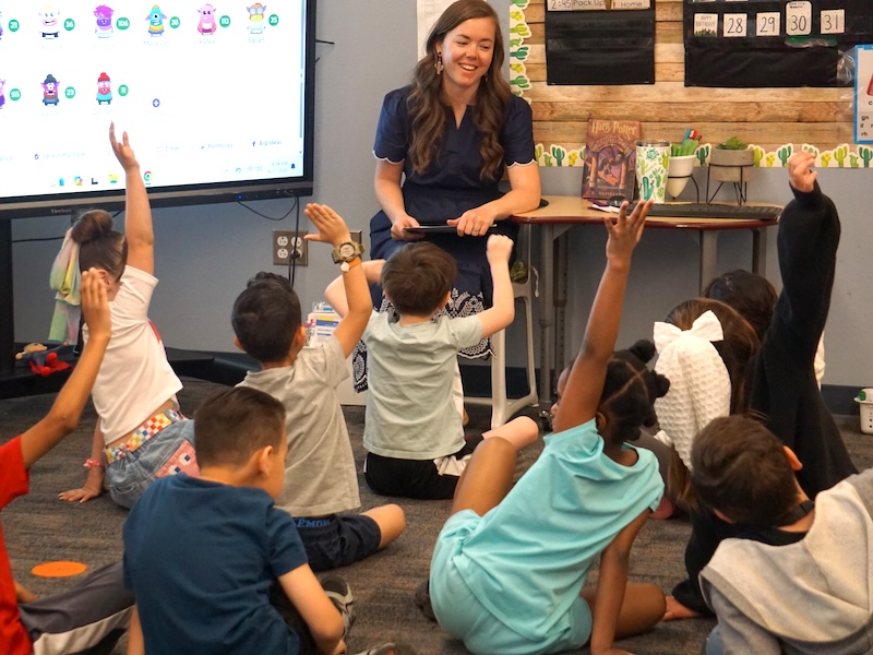 A learning coach, Abby Flores, listens intently to her student in front of her. On a laptop, you can read "UFLI Foundations" and Lesson 6 - Compound Words.