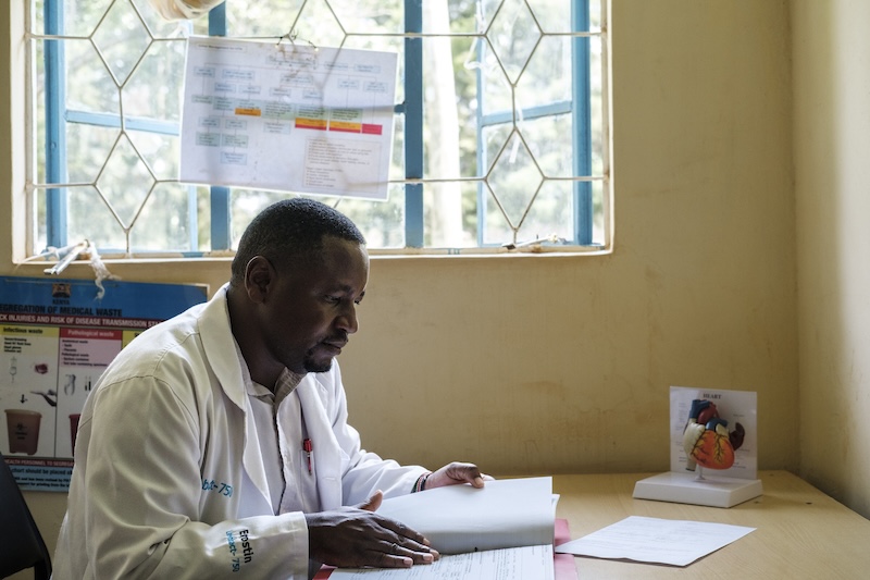 A doctor, wearing a white lab coat, studies a piece of paper.